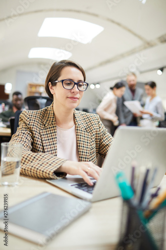 Portrait of contemporary businesswoman using laptop while working in office