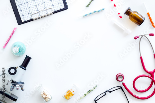Laboratory desk with cardiogram, stethoscope, test tube and microscope on white background top view space for text frame