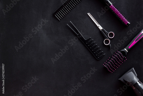 Combs, sciccors and pink hairdresser tools in beauty salon work desk on black background top view space for text