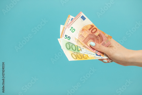 Female hands holding euro banknotes on a blue background.