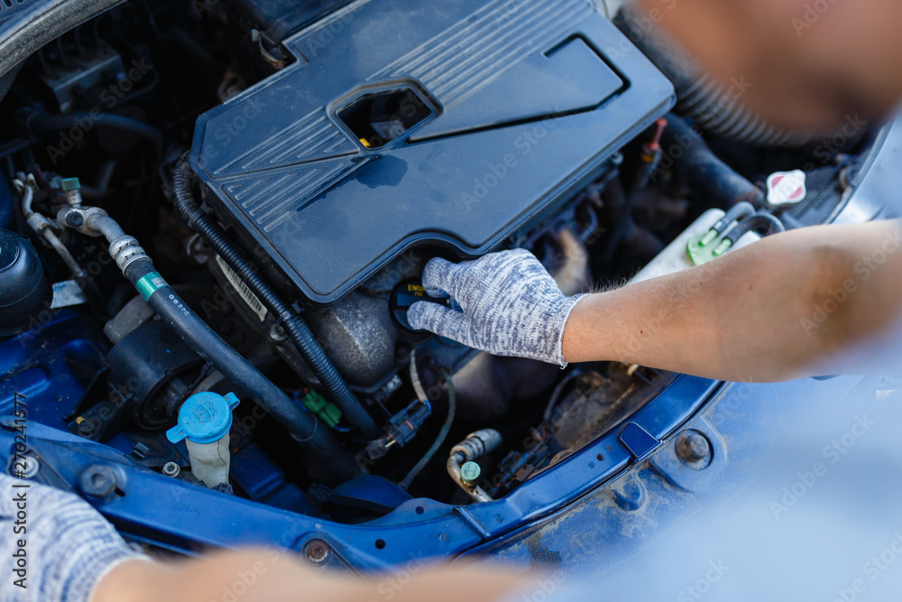 Obraz premium Man's hand unscrews the cap of the oil filler neck of the engine. Mechanic gloves change engine oil, service engine.