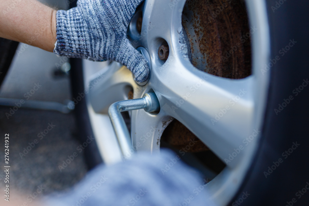 Fototapeta premium Truck maintenance wheel, Close up of a man unscrew wheel nut of the tire manually, and wheel truck mechanic using jack.