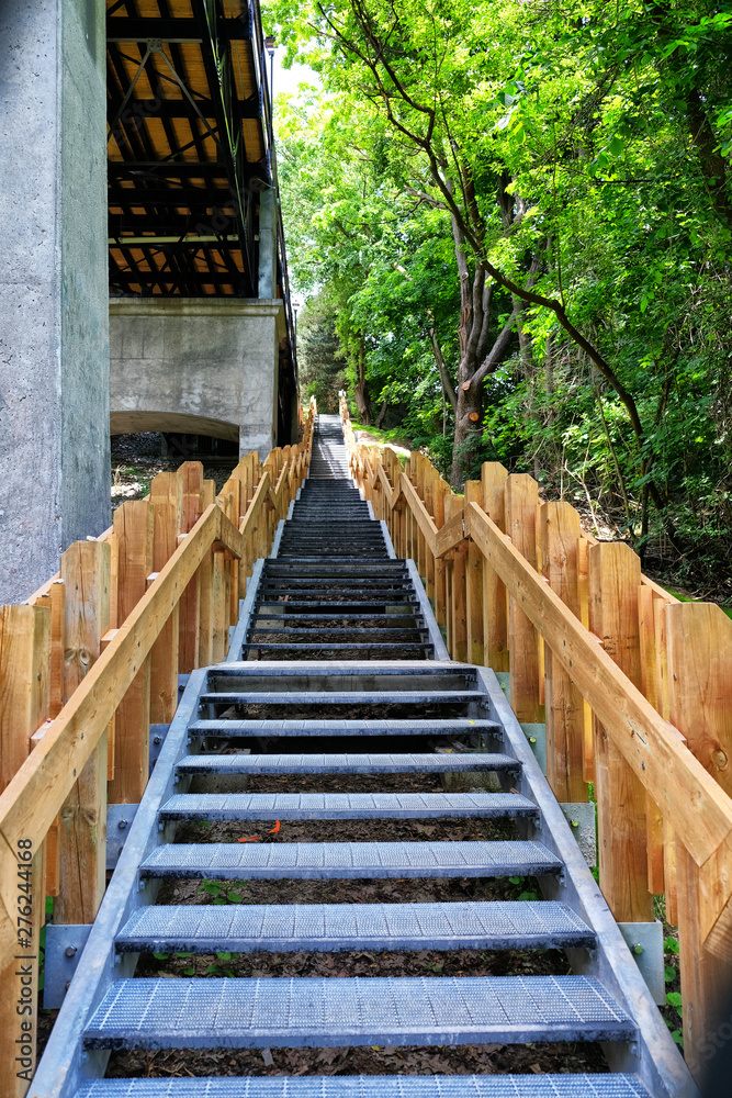 Very steep staircase beside bridge and greenery Very steep staircase beside bridge and greenery