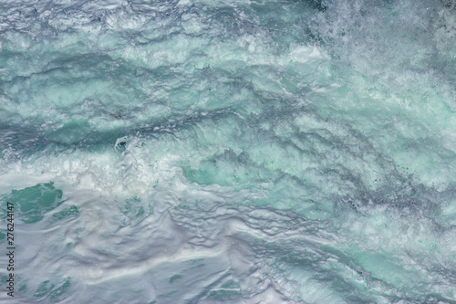 Aquatic background of sea surf waves splashing close up with clear blue green water and white foam
