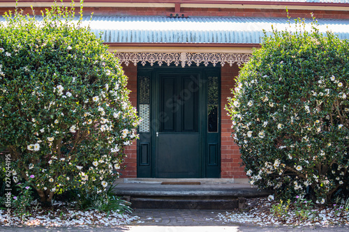 Photography Front house entrance with large green wooden door, bull nose corrugated verandah