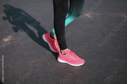 Concept of running track. Close up of Beautiful athletic female slender in the sneakers outdoor.