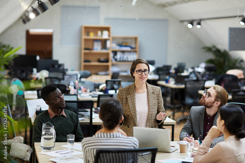 Obraz premium Portrait of modern female manager giving presentation during meeting with colleagues, copy space