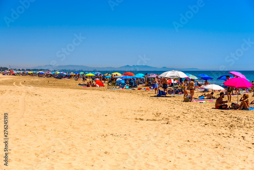 Valencia, Spain - June 23, 2019: Holiday bathers occupying a whole beach to cool off in the sea water and escape the heat wave of the Mediterranean summer. photo