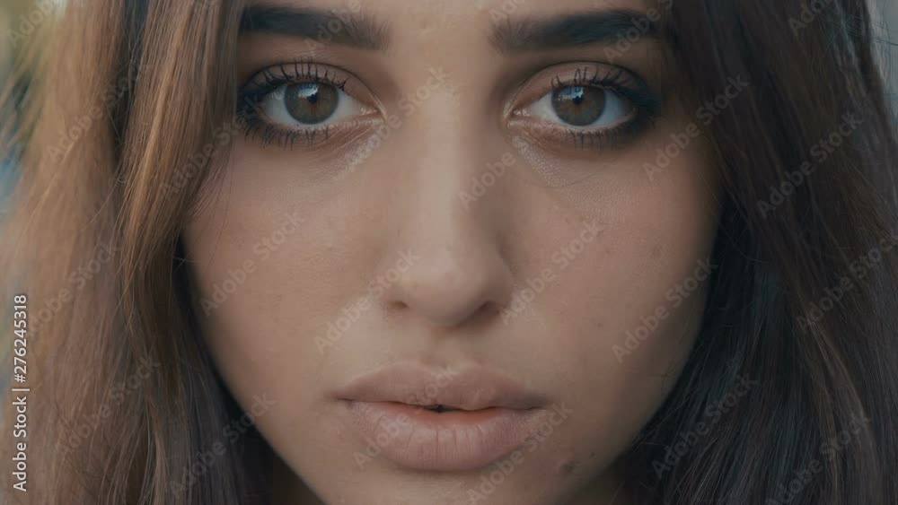 Close-up portrait of beautiful young woman brunette model looking at the camera on a city street background. Girl with big eyes. Close-up portrait of beautiful young woman brunette model looking at the camera on a city street background. Girl with big eyes.