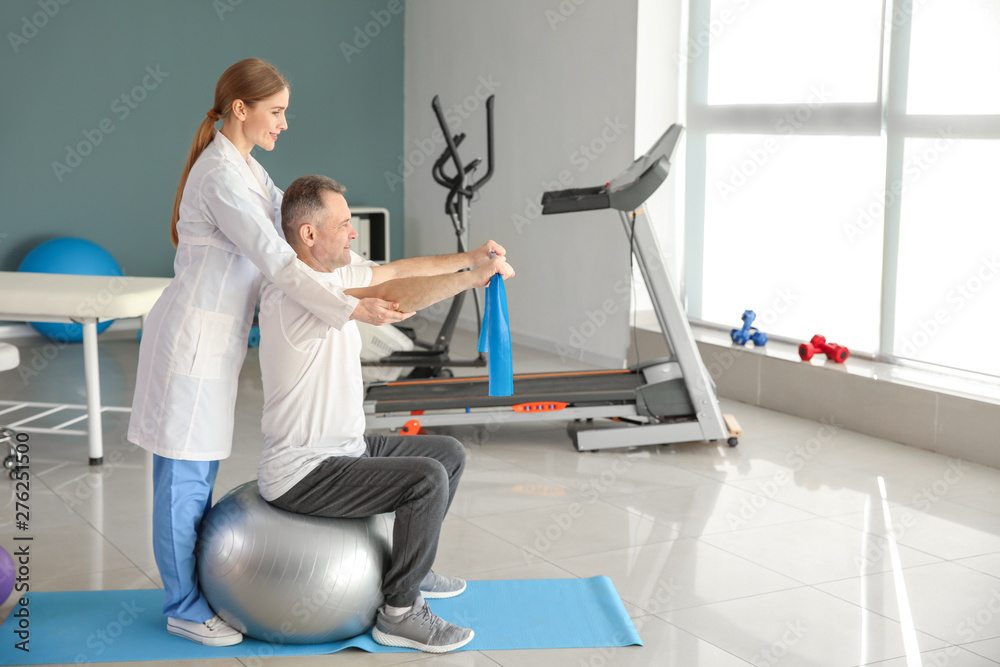 Naklejka premium Physiotherapist working with mature patient in rehabilitation center