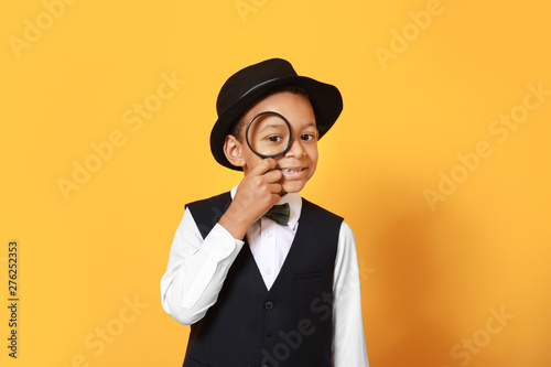 Photography Little African-American detective with magnifier on color background