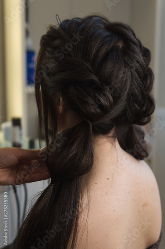 Hairdressing services. Process of creating hairdo, back view. Hairdresser makes hairstyle to client. Beauty industry