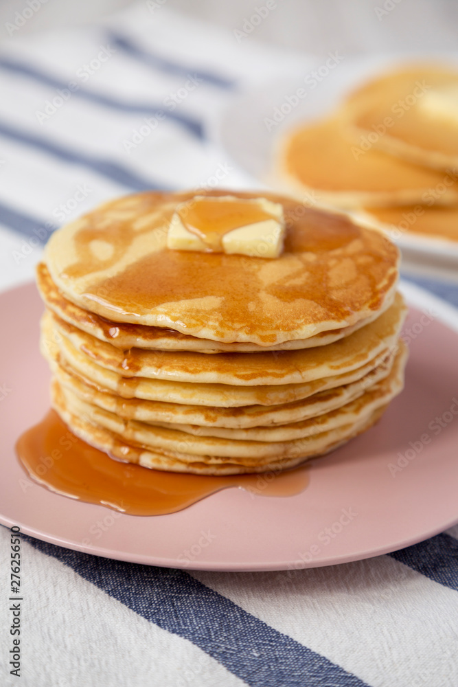 Stack of homemade pancakes with butter and maple syrup on a pink plate, side view. Closeup. Stack of homemade pancakes with butter and maple syrup on a pink plate, side view. Closeup.