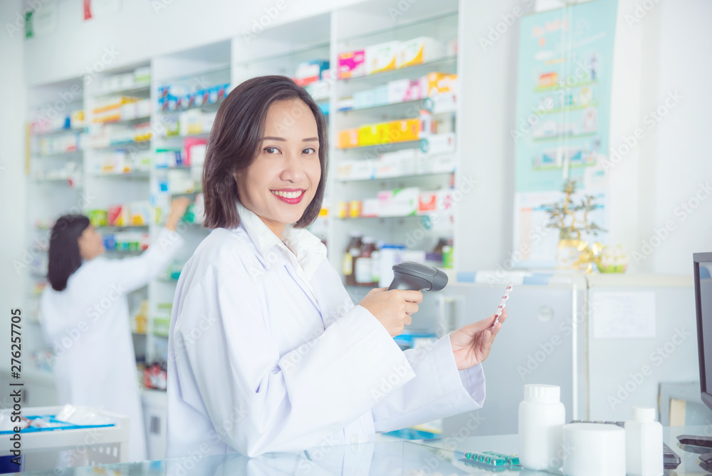 Smiling asian female pharmacist working in pharmacy (chemist shop or drugstore)