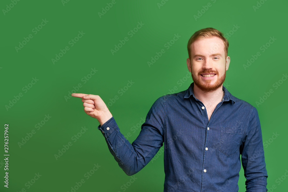Studio portrait of happy handsome young man pointing with index finger Studio portrait of happy handsome young man pointing with index finger