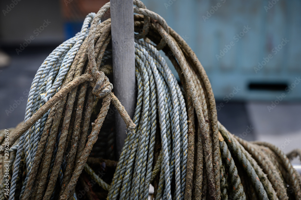 multiple weathered ropes wrapped around a pole on a fishing boat