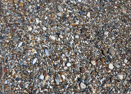 Multi-colored large sea pebbles of various shapes on the sandy shore of the Mediterranean sea for background