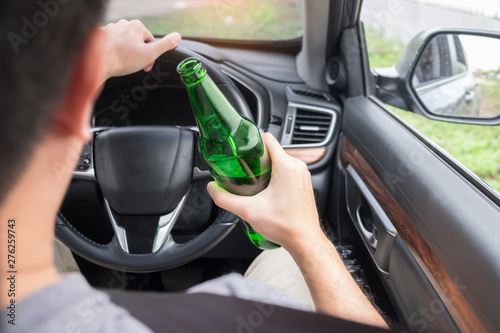 Don't Drink for Drive concept, Young Drunk man drinking bottle of beer or alcohol during driving the car dangerously