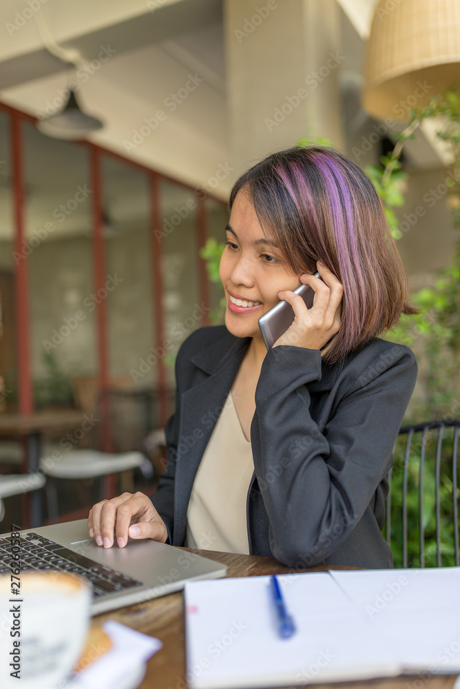 Portrait of Asian woman smiling while using cellphone and laptop Portrait of Asian woman smiling while using cellphone and laptop