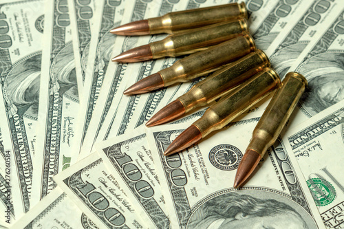 Rifle cartridges on dollars. Concept for crime, contract killing, paid assassin, terrorism, war, global arms trade, weapons sale. Illegal hunting, poaching