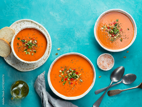 Gaspacho soup on blue tabletop. Three bowls of traditional spanish cold soup puree gaspacho or gazpacho on bright blue background with copy space for text. Top view or flat lay.