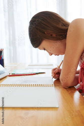 Serious schoolgirl concentrated on drawing in her album at art class in school
