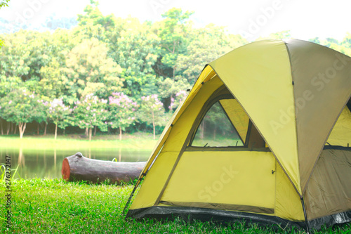 Camping green tent in forest near lake