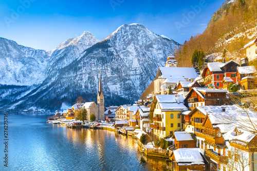 Classic postcard view of famous Hallstatt lakeside town in the Alps with traditional passenger ship on a beautiful cold sunny day with blue sky and clouds in winter, Austria