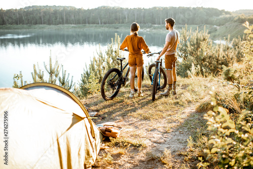 Valokuva Young couple standing with mountain bicycles at the campsite, traveling in the f
