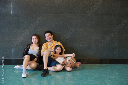 full shot group of happiness asian family father, mother, son and daughter taking picture in sitting pose after playing basketball in sport club with happy smiling face during holiday vacation © feeling lucky