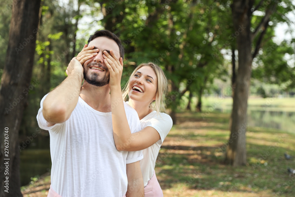 medium shot, young lovely couple caucasian in white dress playing blindfolded with happy face and laughing in park outdoor during summer medium shot, young lovely couple caucasian in white dress playing blindfolded with happy face and laughing in park outdoor during summer