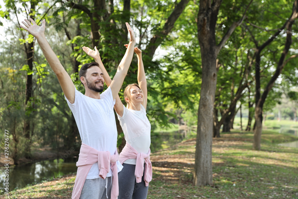 medium shot, young couple caucasian sporty people in white shirt raising their hands with relaxation and happy face in the park during summer