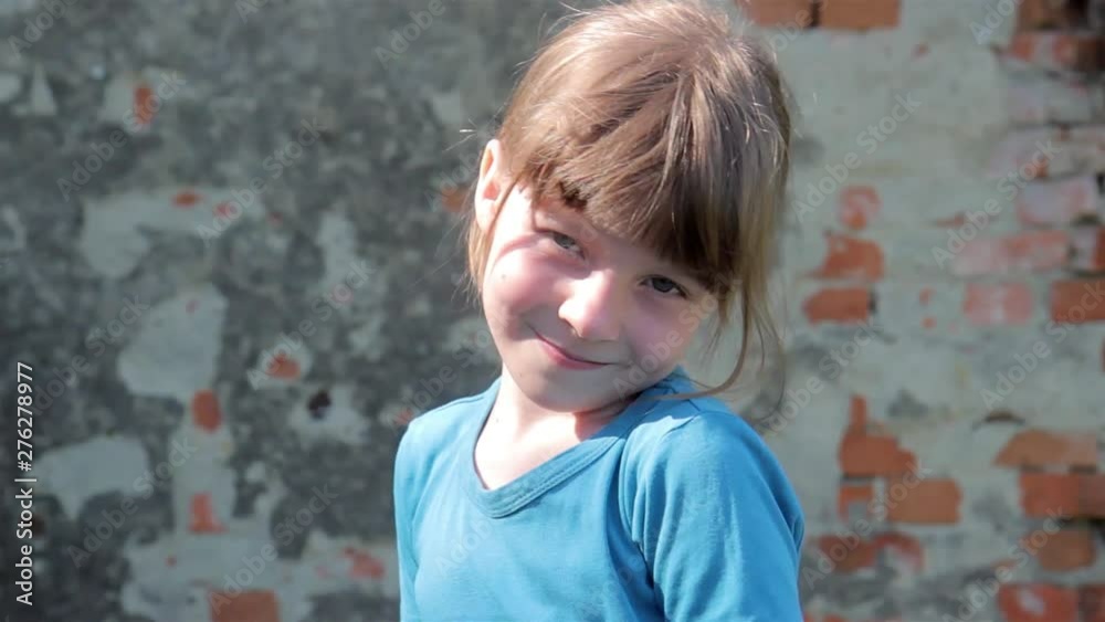 An interesting girl poses in front of the camera on the background of the old brick wall