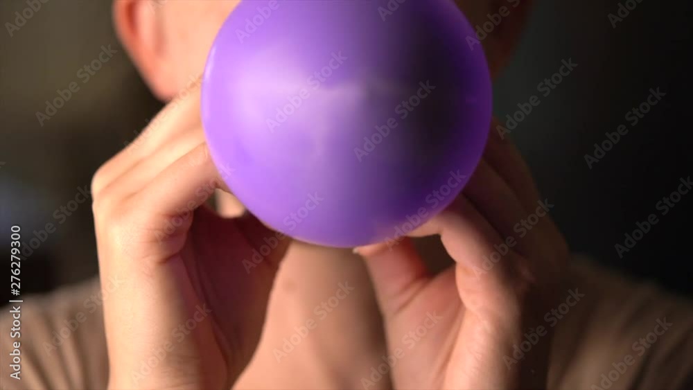Untitled ProjectThis close up macro real time video shows a caucasian woman blowing up a  purple balloon towards the camera.