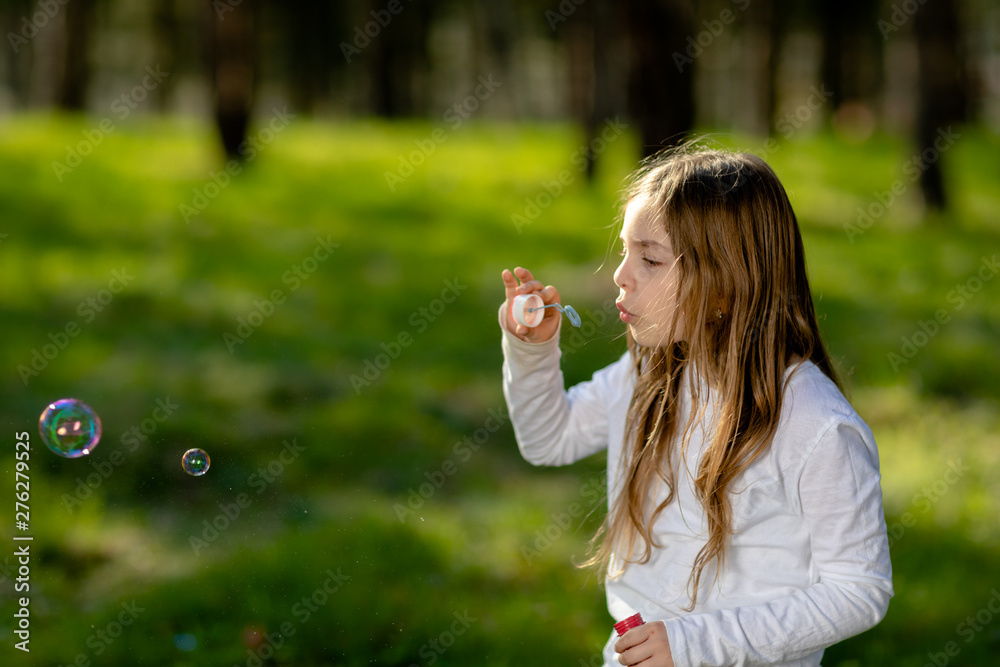 young girl blowing soap bubbles in park young girl blowing soap bubbles in park