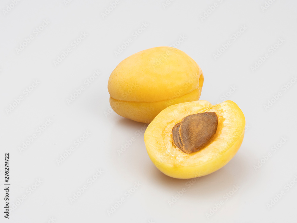 Yellow apricots on a white background, close-up. Whole apricot and half with bone. Still life. Yellow apricots on a white background, close-up. Whole apricot and half with bone. Still life.