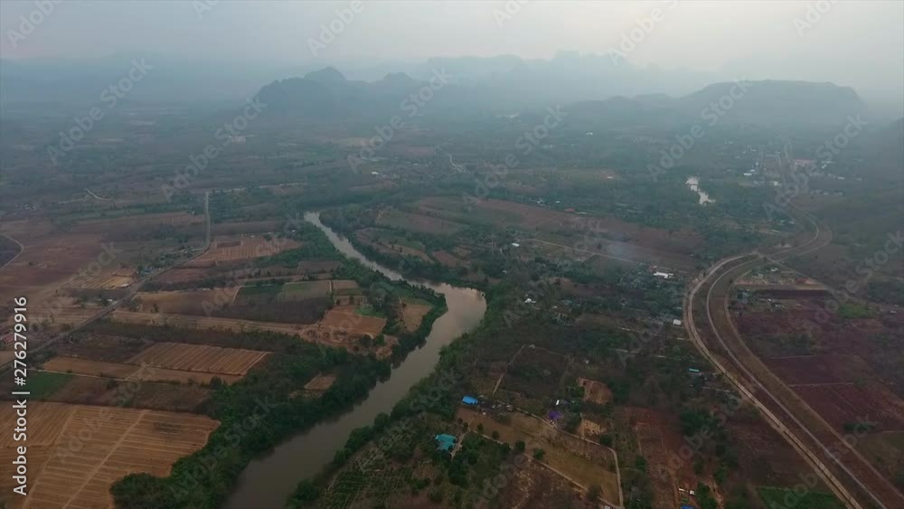An aerial shot of a river cutting through a farm lands 