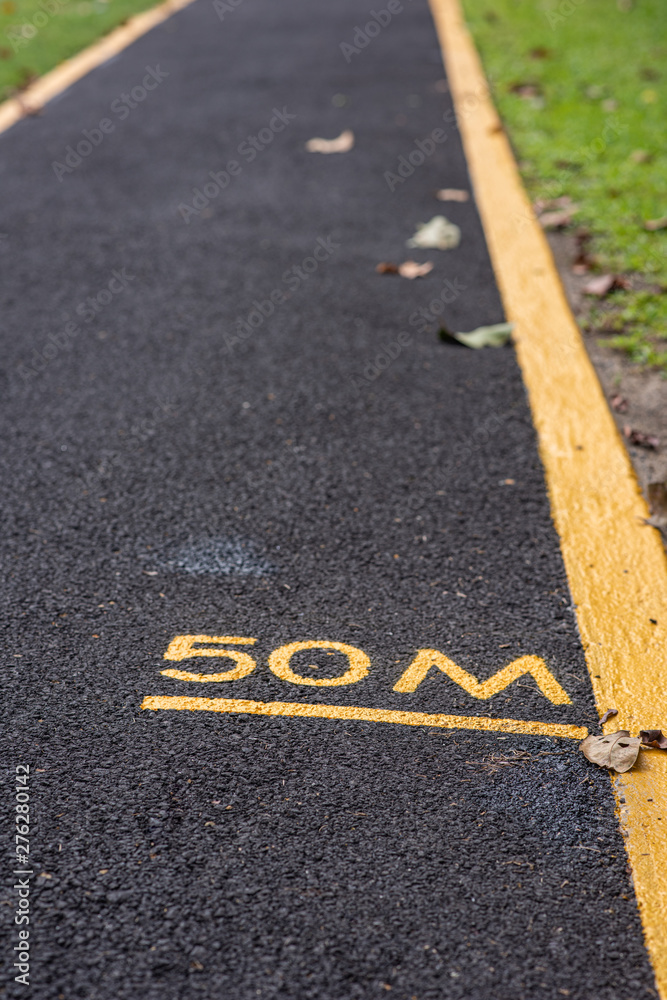 50M (meters), with yellow letters and line marked on a asphalt running track, awaiting for any runners to passed. 