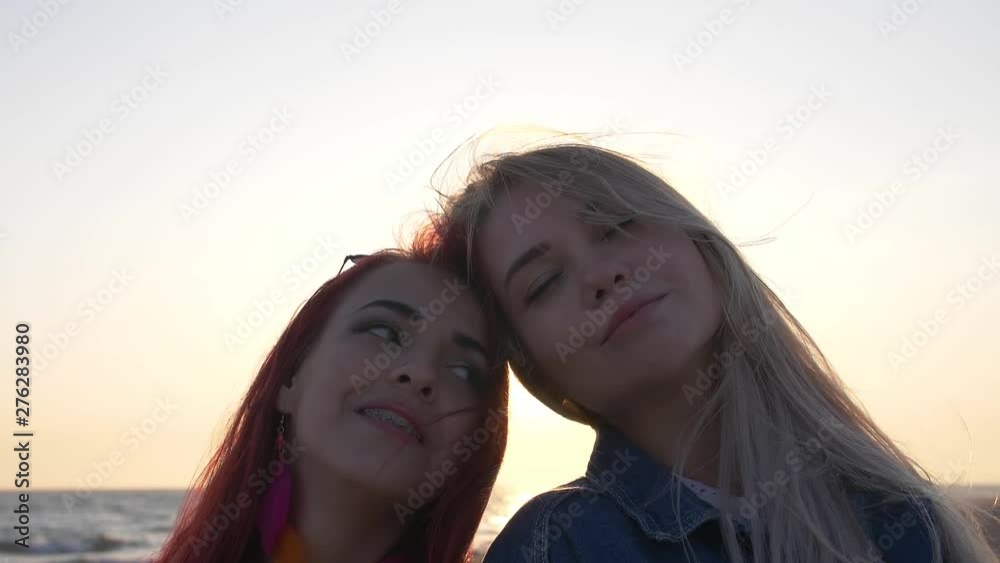 two friends head to head smiling against the sunset over the sea two friends head to head smiling against the sunset over the sea