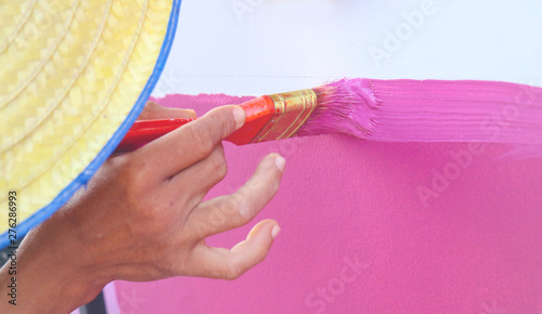 painter painting the wall, Man holding in hand paintbrush, Drawing paint on wall