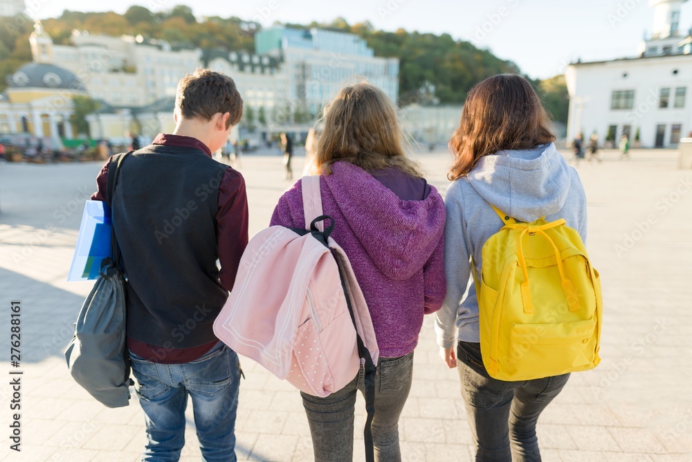 View from the back on three high school students with backpacks. View from the back on three high school students with backpacks.
