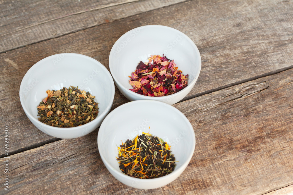 Aromatic dry tea in bowls on wooden background Aromatic dry tea in bowls on wooden background