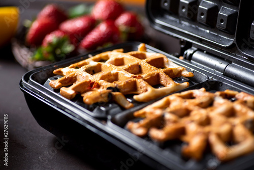 Fotografia Waffle pastry baking on a waffle maker close up