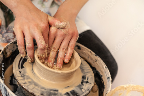 A pottery process - young girl's feminine hands making clay bowl or mug on Potter's wheel