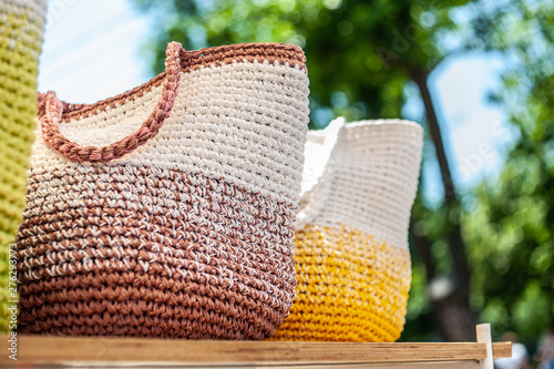 A few crochet colored bag standing on play wood plate outdoor in the park, a day light