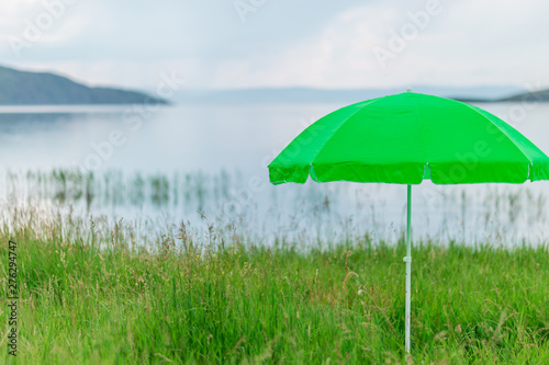 Modern green neon umbrella for sun on beach against sea