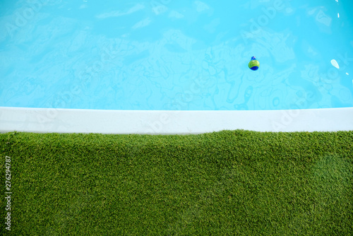 yellow blue ball float on the swimming pool, swimming pool with artificial grass.