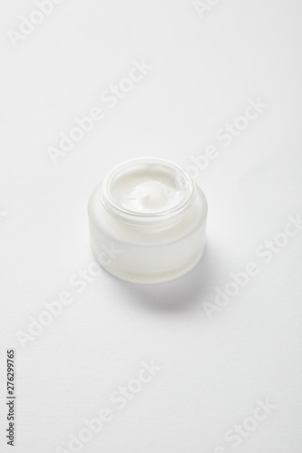 open glass jar with face cream on white