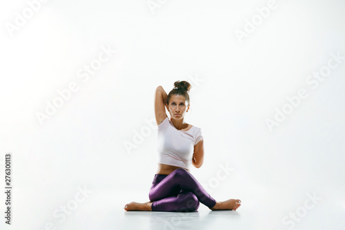 Sporty young woman doing yoga practice isolated on white studio background. Fit flexible female model practicing. Concept of healthy lifestyle and natural balance between body and mental development.