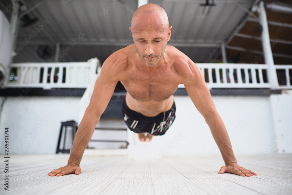 Young and handsome man is doing some push-ups. He is using loops for that Young and handsome man is doing some push-ups. He is using loops for that